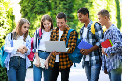 Students gathered outdoors looking at laptop.